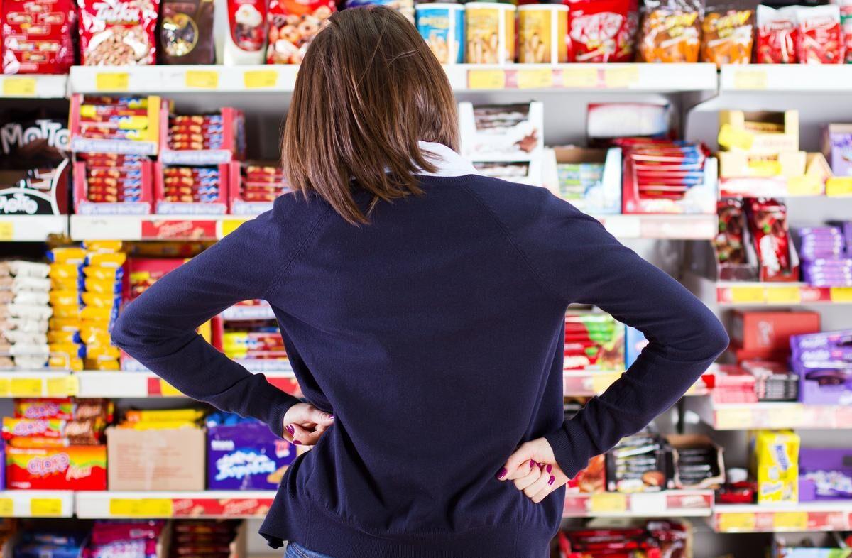 woman looking at grocery store shelf with hands on hips